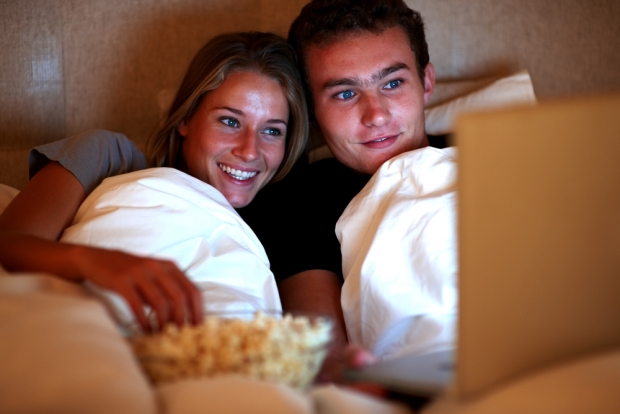 Una pareja en la cama viendo una película erótica